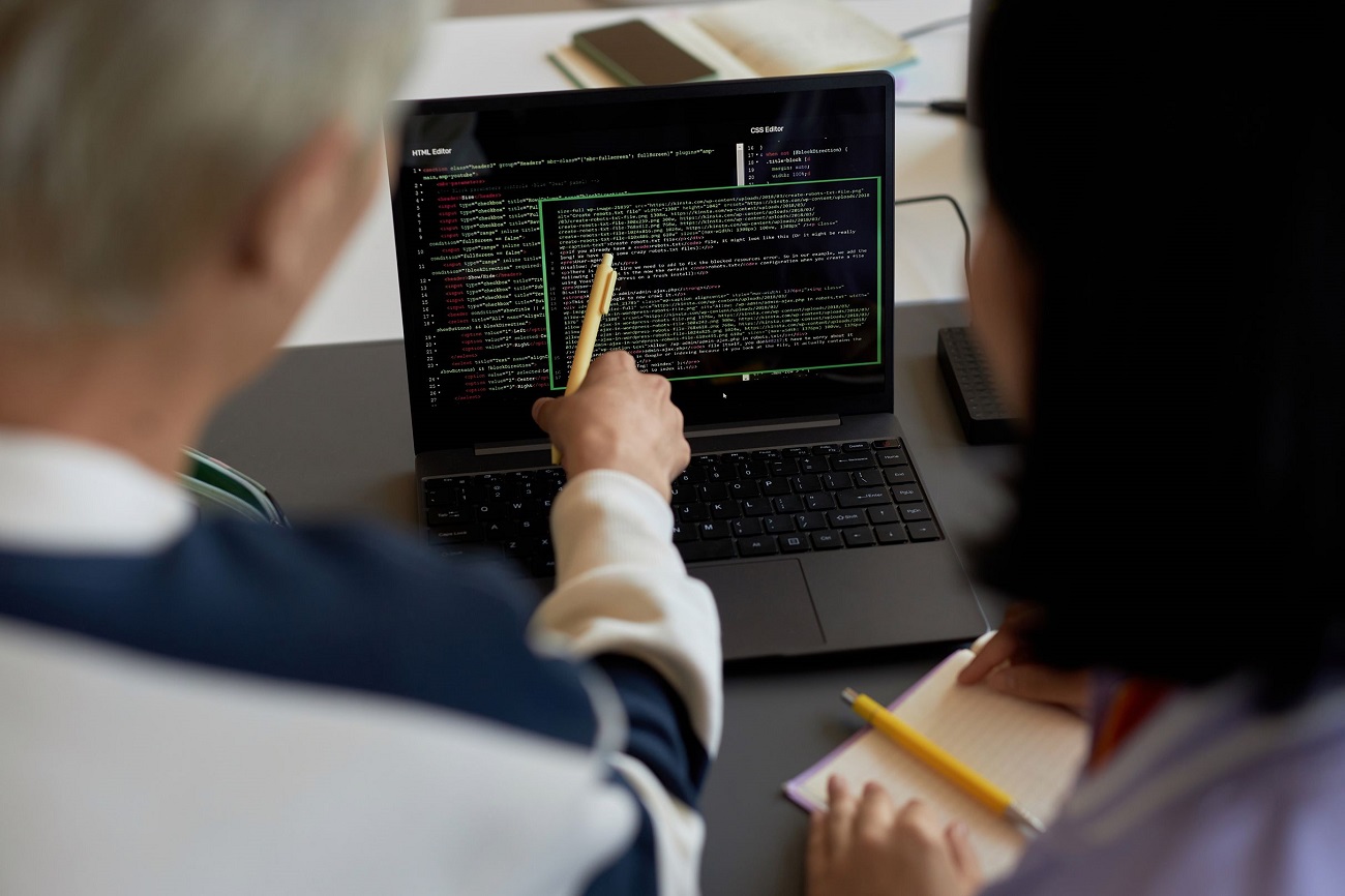 guy-with-pen-pointing-at-codes-on-laptop-screen-du-ESE25VA